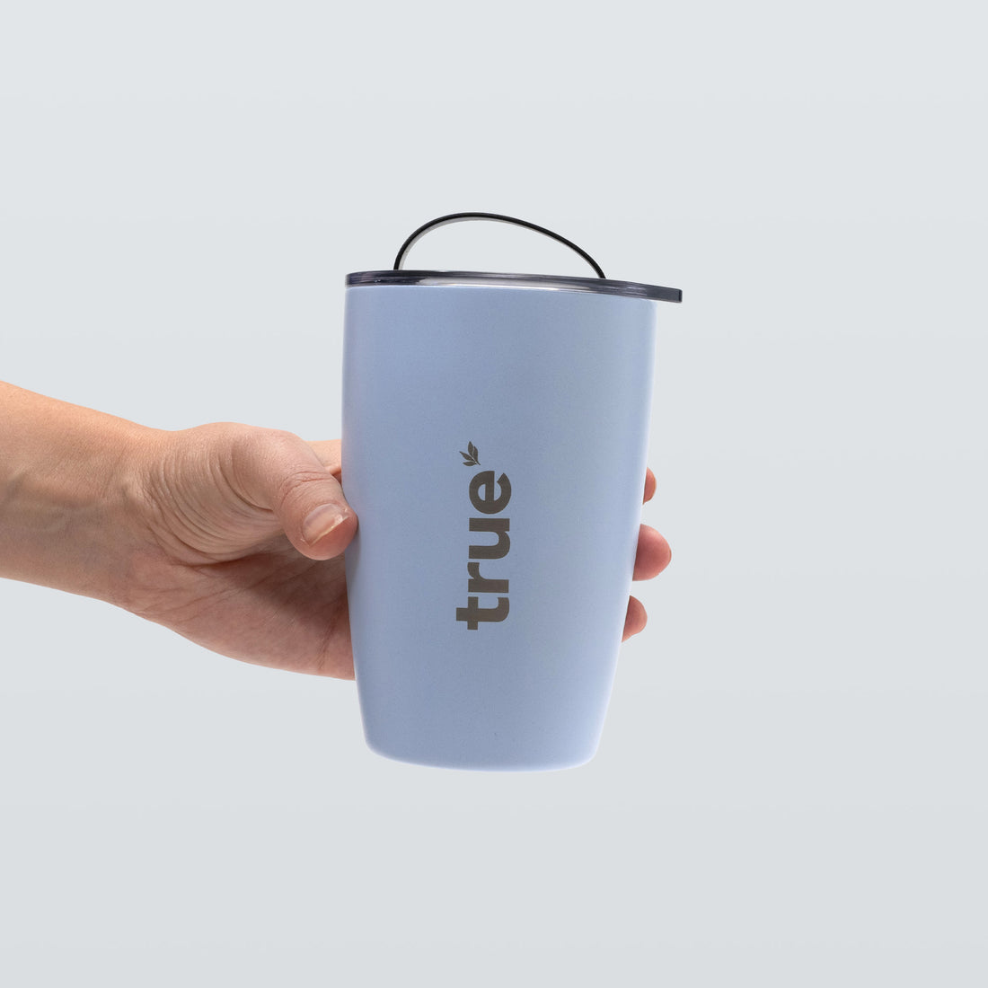 Ocean blue insulated travel tumbler with spill‑proof lid and "true" logo held in hand — 12oz stainless steel travel cup for coffee and tea, portable reusable tumbler