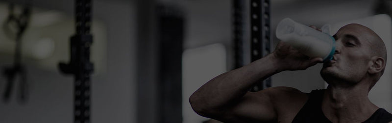 Muscular athlete in a gym drinking from a protein shaker bottle — rugby supplements banner promoting protein shakes and sports nutrition for rugby players.
